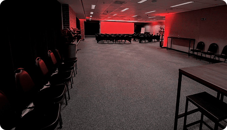 imagem do exodus, um telão de led com luzes vermelhas, cadeiras de auditório