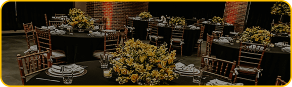 imagem de mesas redondas, com cadeiras de madeira. mesa posta e flores amarelas